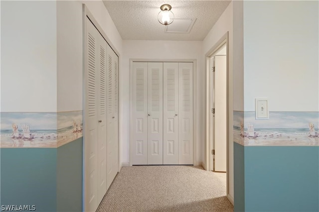 hall featuring light colored carpet and a textured ceiling