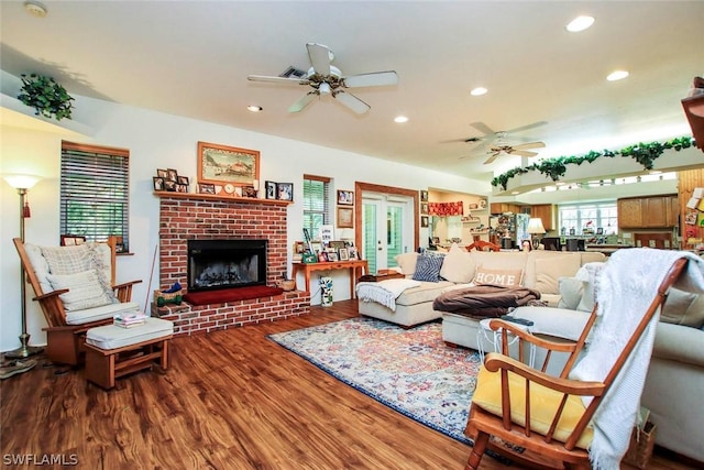 living room featuring a brick fireplace, hardwood / wood-style flooring, and ceiling fan