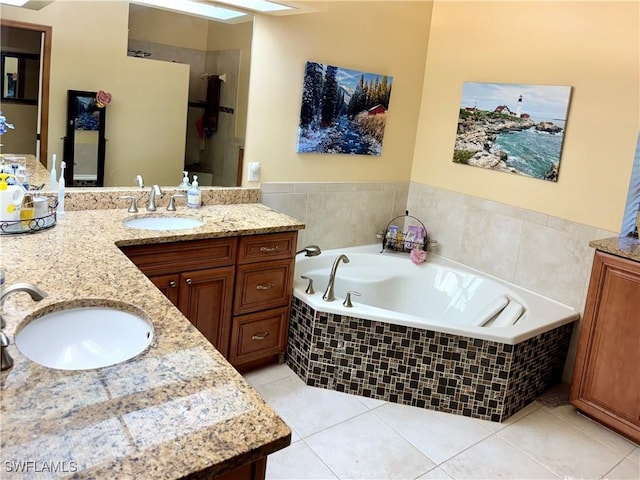 bathroom with tile patterned flooring, vanity, and tiled bath