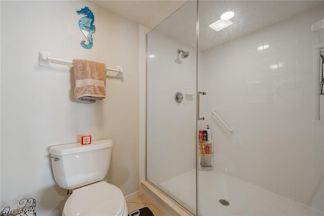 bathroom with a shower with door, toilet, and tile flooring