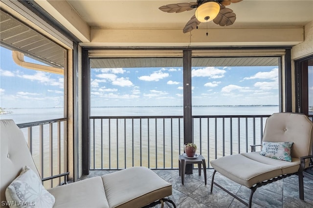 sunroom / solarium with a healthy amount of sunlight, ceiling fan, and a water view