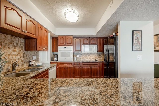 kitchen with light stone counters, a textured ceiling, sink, backsplash, and black appliances