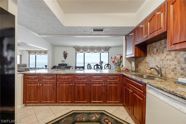 kitchen featuring dishwasher, light tile flooring, tasteful backsplash, refrigerator, and light stone countertops