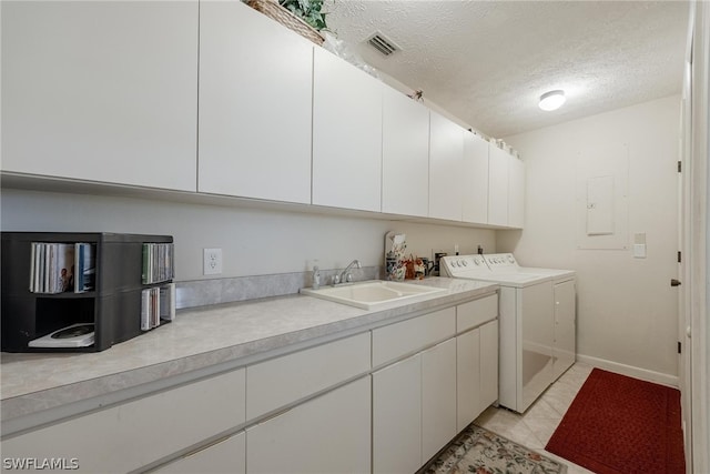 laundry area featuring independent washer and dryer, a textured ceiling, cabinets, and sink