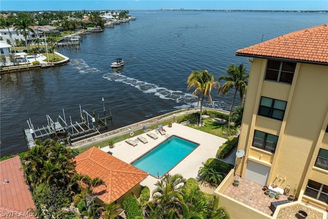 view of swimming pool with a patio area, a water view, and a dock