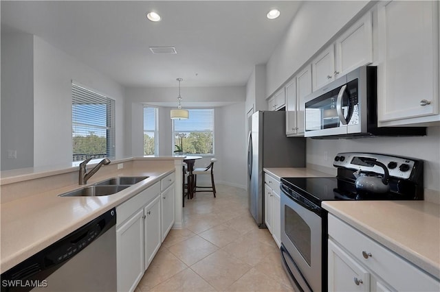 kitchen featuring decorative light fixtures, stainless steel appliances, plenty of natural light, white cabinetry, and sink