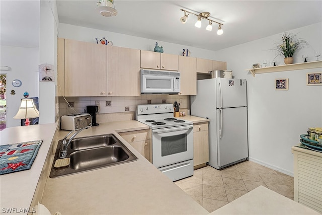 kitchen with white appliances, rail lighting, sink, tasteful backsplash, and light tile floors