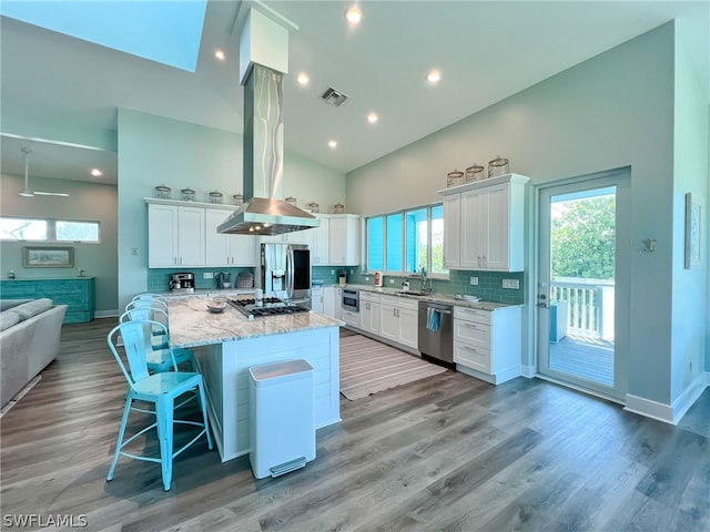 kitchen featuring light stone countertops, appliances with stainless steel finishes, tasteful backsplash, white cabinetry, and hardwood / wood-style floors