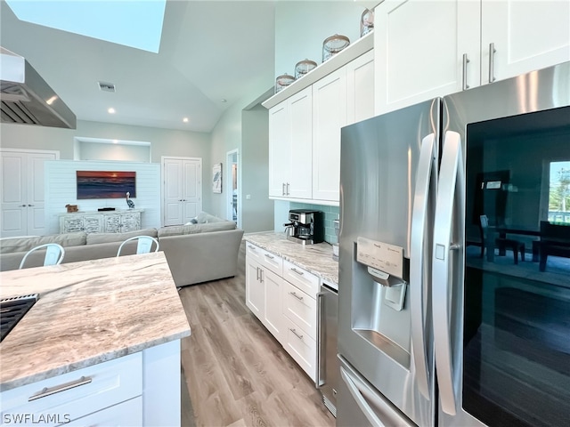 kitchen featuring light wood-type flooring, white cabinetry, backsplash, light stone counters, and stainless steel fridge with ice dispenser