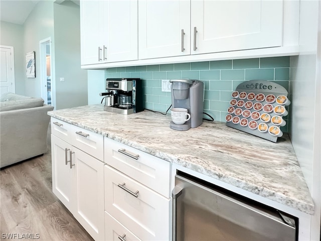 kitchen featuring tasteful backsplash, light stone counters, white cabinets, and light wood-type flooring