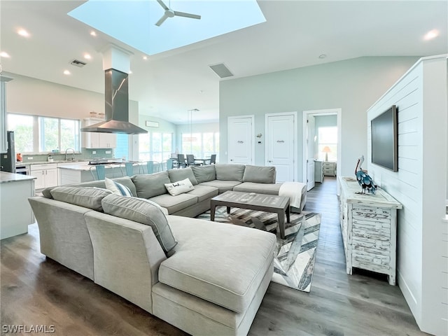 living room with sink, ceiling fan, lofted ceiling with skylight, and dark hardwood / wood-style floors