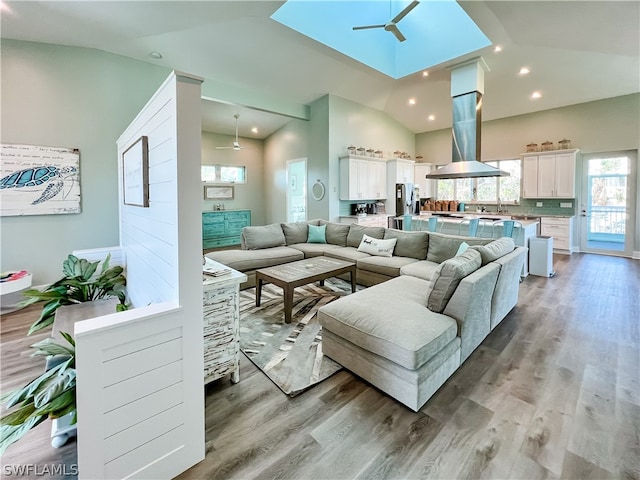 living room featuring high vaulted ceiling, ceiling fan, sink, and light wood-type flooring