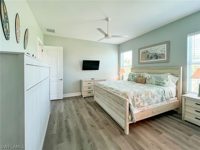 bedroom with hardwood / wood-style flooring, ceiling fan, and multiple windows