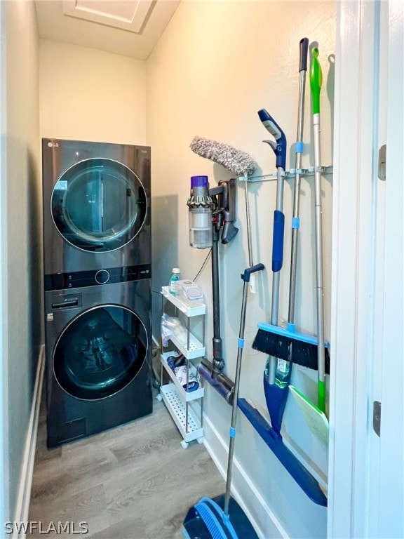 laundry area featuring stacked washer / dryer and light hardwood / wood-style floors