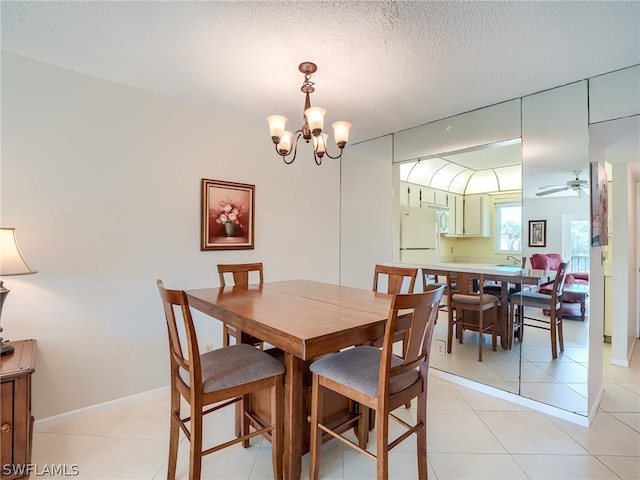 tiled dining area featuring ceiling fan with notable chandelier and a textured ceiling