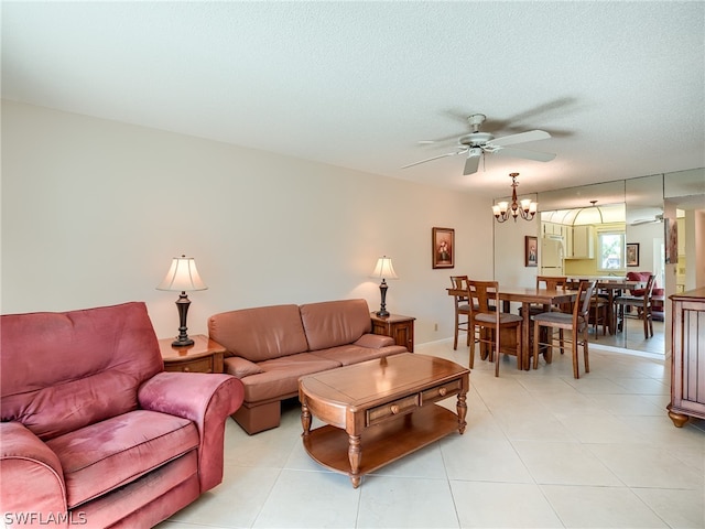 living room with tile flooring, ceiling fan with notable chandelier, and a textured ceiling