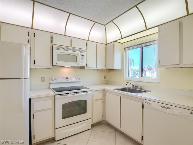 kitchen featuring light tile floors, white appliances, and sink