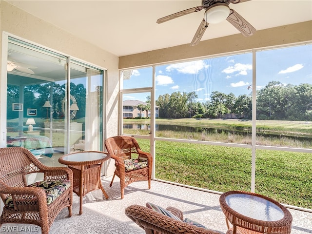 sunroom with ceiling fan and a water view