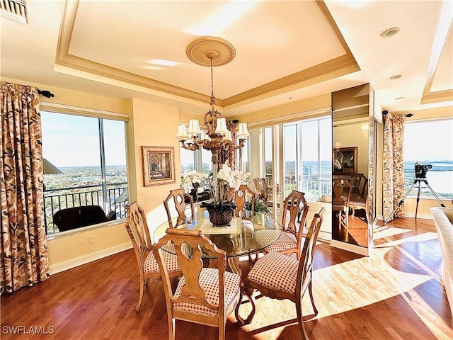 dining room featuring hardwood / wood-style floors, a raised ceiling, and a chandelier