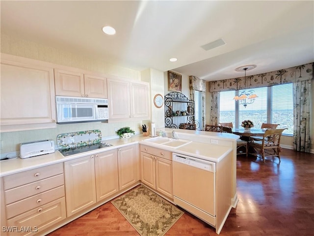 kitchen featuring sink, dark hardwood / wood-style floors, kitchen peninsula, decorative light fixtures, and white appliances