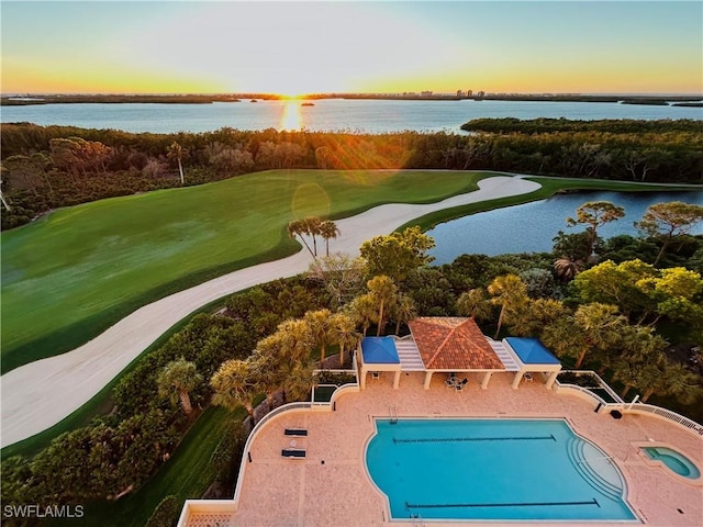 pool at dusk featuring a water view