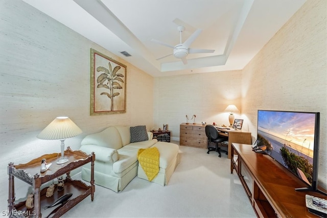 living room with a raised ceiling and ceiling fan