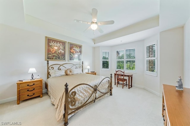 carpeted bedroom featuring ceiling fan and a tray ceiling