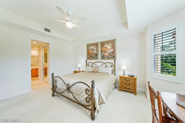 carpeted bedroom with a raised ceiling, ceiling fan, and ensuite bathroom