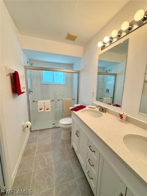 bathroom featuring a shower with shower door, toilet, tile flooring, and double sink vanity