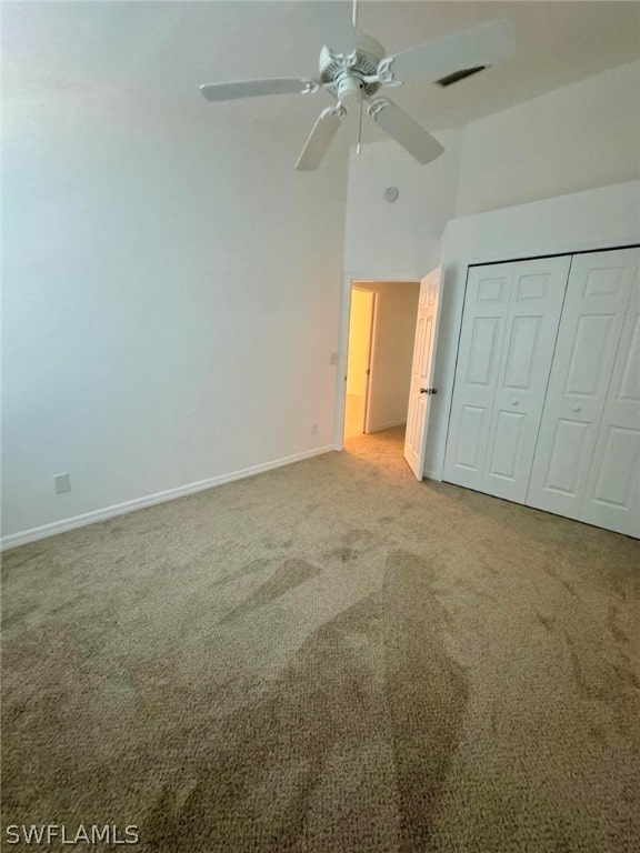 unfurnished bedroom with light carpet, a closet, ceiling fan, and high vaulted ceiling