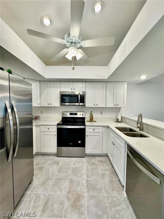 kitchen with white cabinets, sink, appliances with stainless steel finishes, and a raised ceiling