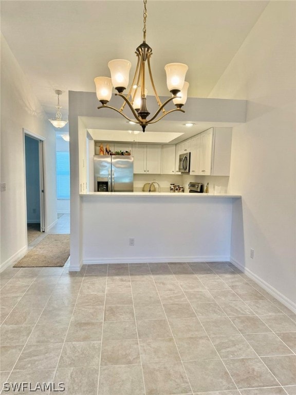 kitchen with appliances with stainless steel finishes, pendant lighting, an inviting chandelier, and white cabinetry