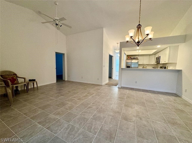 unfurnished living room featuring ceiling fan with notable chandelier, high vaulted ceiling, and tile flooring