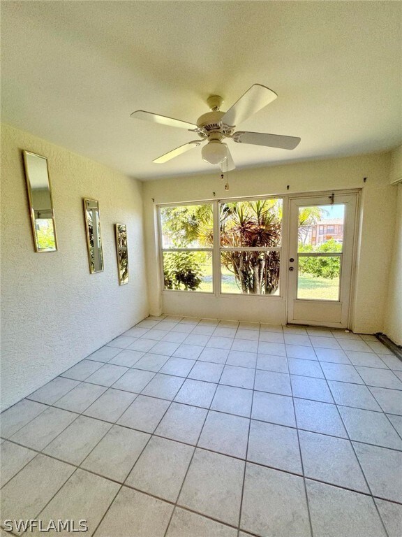 tiled spare room featuring ceiling fan