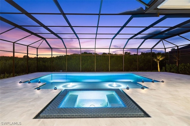 pool at dusk with an in ground hot tub, a lanai, and a patio