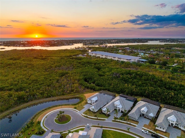 aerial view at dusk featuring a water view