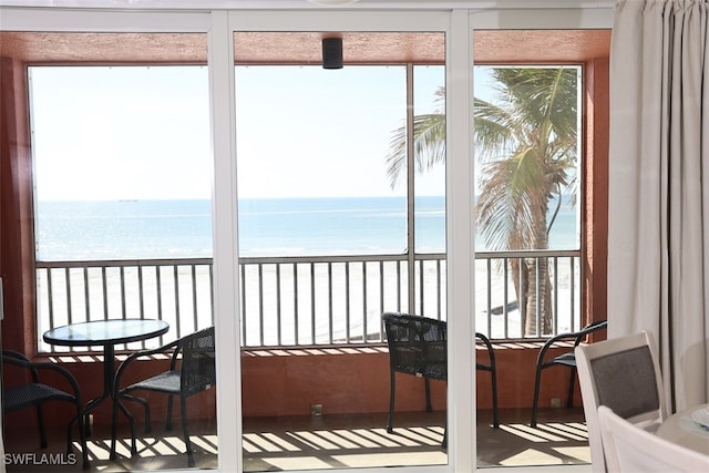 sunroom with a water view and a view of the beach