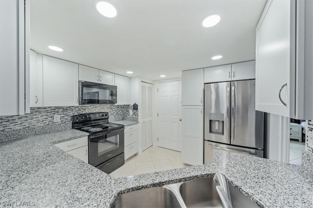 kitchen featuring black appliances, decorative backsplash, light tile patterned floors, light stone counters, and white cabinetry