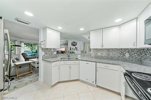 kitchen with light stone countertops, white dishwasher, white cabinetry, and sink