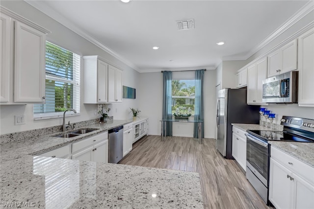 kitchen featuring white cabinetry, stainless steel appliances, light hardwood / wood-style floors, light stone counters, and sink