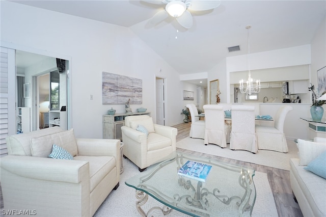 living room featuring ceiling fan with notable chandelier, light hardwood / wood-style flooring, and lofted ceiling