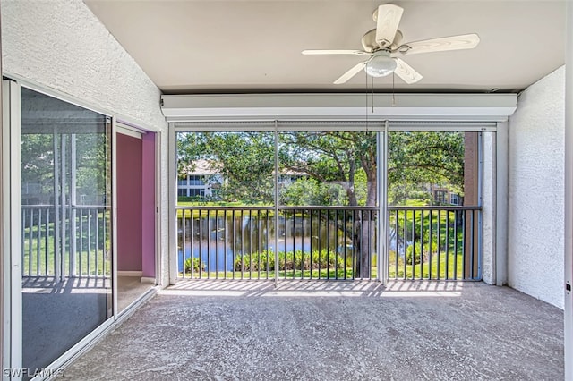 unfurnished sunroom with ceiling fan and a water view