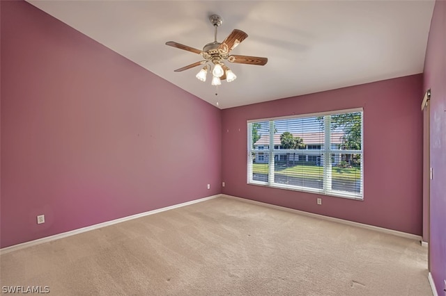 carpeted spare room featuring vaulted ceiling and ceiling fan