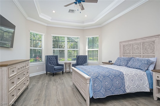 bedroom with a raised ceiling, ornamental molding, ceiling fan, and light hardwood / wood-style floors