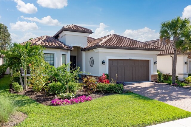 mediterranean / spanish house featuring a front yard and a garage