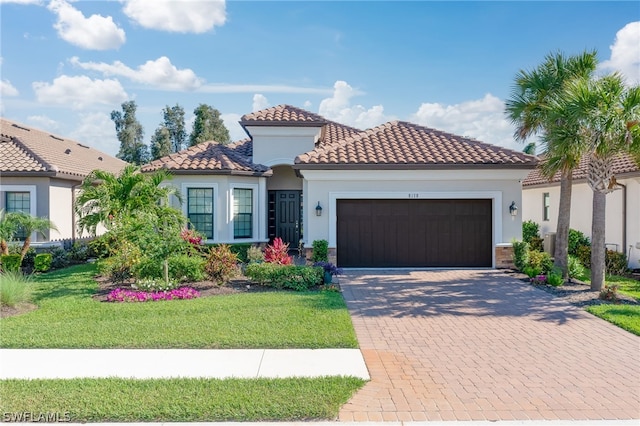 mediterranean / spanish house featuring a garage and a front lawn