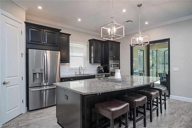 kitchen featuring light stone counters, a center island, hanging light fixtures, appliances with stainless steel finishes, and a kitchen breakfast bar