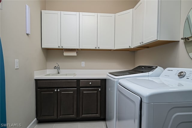 laundry room featuring cabinets, light tile patterned floors, sink, and washing machine and clothes dryer