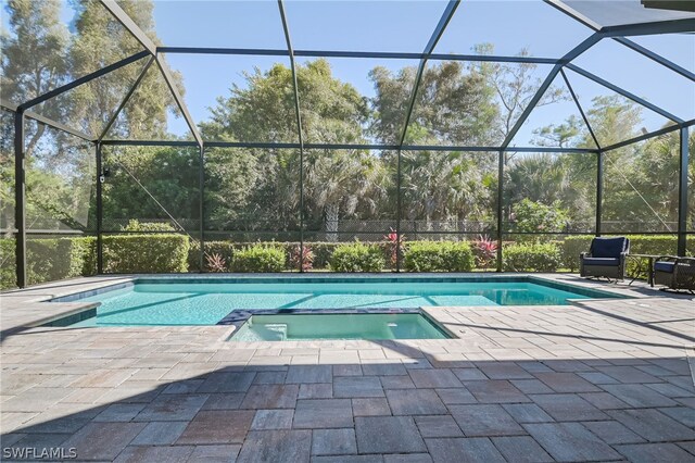 view of pool with a lanai, an in ground hot tub, and a patio