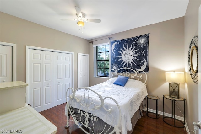 bedroom with dark wood-type flooring, ceiling fan, and multiple closets